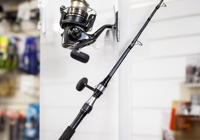 Spinning rod and reel combo displayed on a clean shop wall with subtle saltwater styling